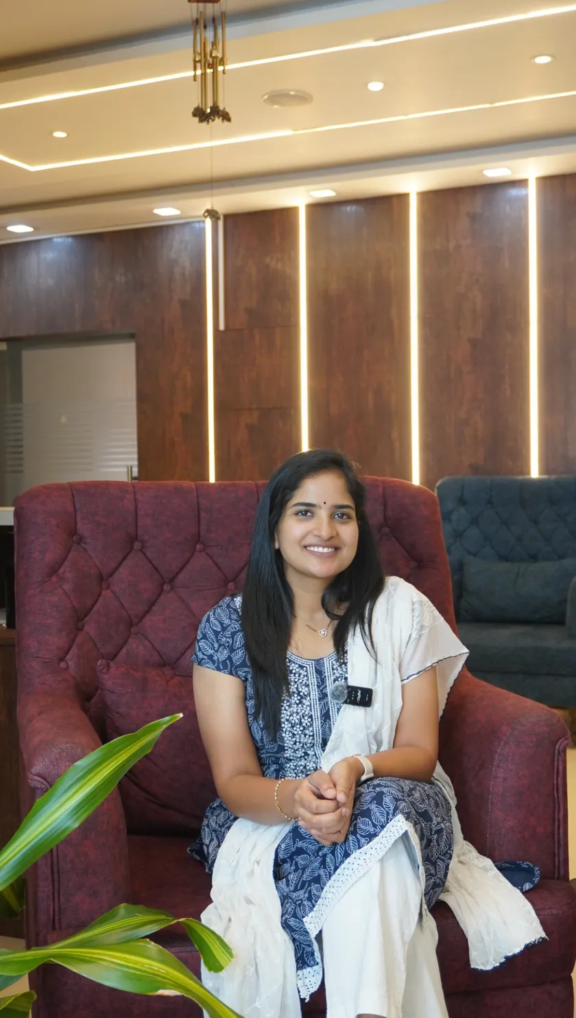 Dr. Srilakshmi Champati smiling, seated in a blue and white outfit